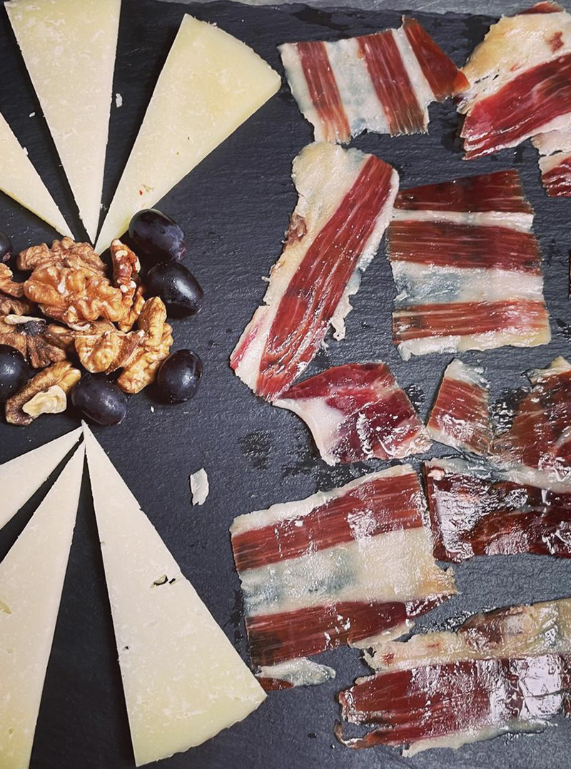 Spanish platter of sliced Jamón Ibérico and cheese, served with olives and walnuts
