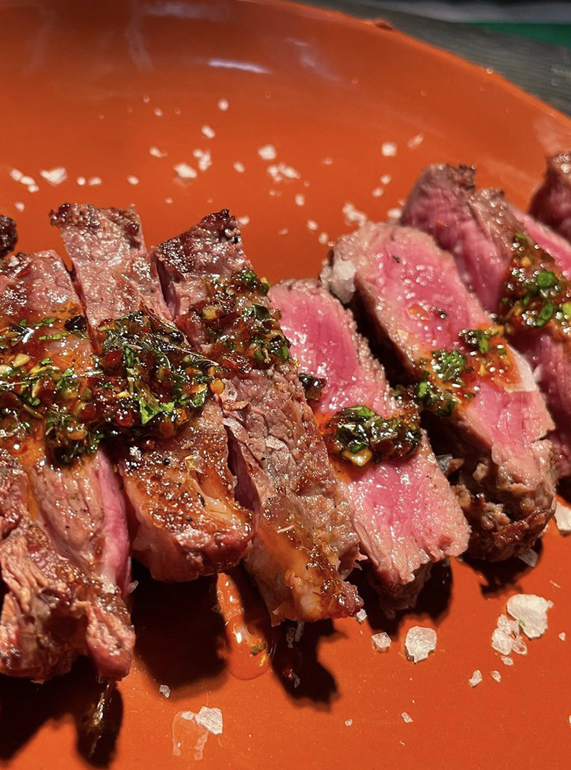 A photo of a juicy steak with Chimichurri sauce at Bocas in London